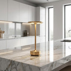 Gold lamp on a marble kitchen counter with a modern kitchen in the background